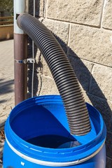 Blue plastic rain water barrel. watering the garden. Water saving. Water supply for dry summer. Rainwater drainage.