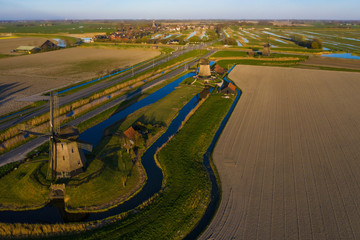 Aerial view on three dutch windmills bathing in sunlight with a blue sky 