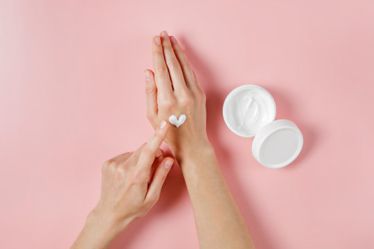 Revitalizing Hand Cream For Healing And Recovery After Excessive Use Of Soap And Disinfectants. Young Woman Applying Moisturizing Lotion. Copy Space, Close Up, Pink Background, Flat Lay, Top View.