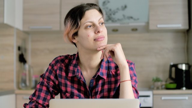 Concerned Russian Woman Looking Away Thinking Solving Problem At Home Office. Woman Working On Laptop Computer. Stay At Home In Quarantine Due To Coronavirus 