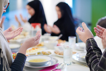 traditional muslim family praying before iftar dinner