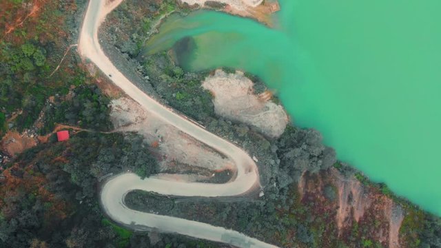 Birdeye view of a very curvy S shaped road section along the Marshyangdi River, connecting the city of Besi Sahar with BP highway. Aerial wide shot from a drone on an overcast day soft light.