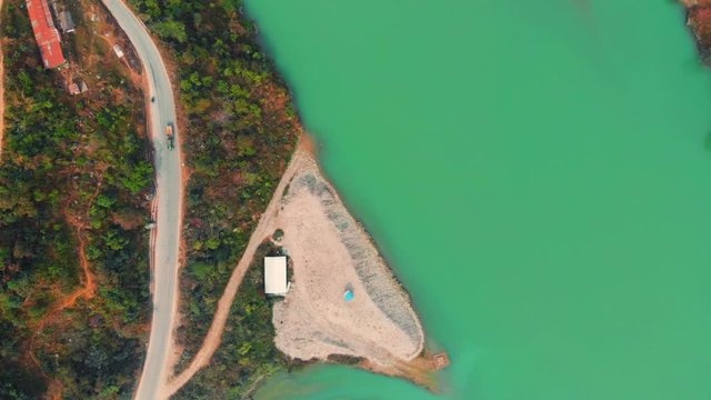 Birdeye view of a road section along the Marshyangdi River, connecting the city of Besi Sahar with BP highway. Aerial wide shot moving forward from a drone on an overcast day soft light.