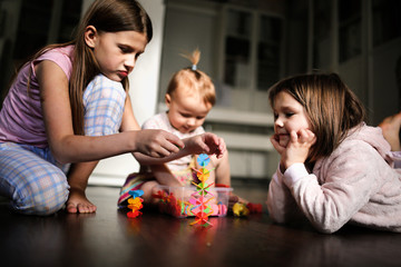 siblings play together with toys on dark floor