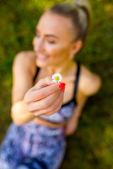 Frau mit Blume, Gänseblümchen, lacht und genießt die Sonne, liegend im Gras , draufsicht