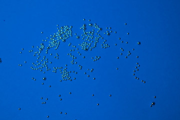 A lot of silver little balls on a blue background. Abstract