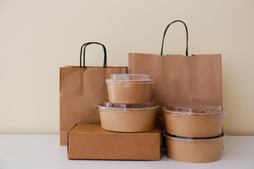 Bunch of blank disposable containers for takeout food stacked with paper bags and boxes with copy space for brand's logo. Close up shot of eco friendly to go carton bowls on table.