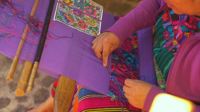 Guatemalan woman weaving blanket on a loom High Angle
