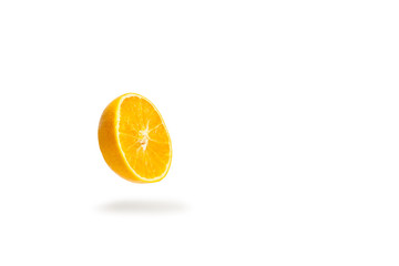 Naranja cortada por la mitad levitando y proyectando sombra sobre un fondo blanco liso y aislado....