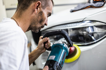 Car detailing - Hands with orbital polisher in auto repair shop. Selective focus.