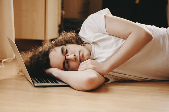 Teenager sleeping on laptop.
