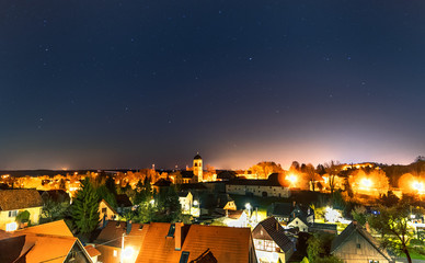 Nächtlicher Blick über Dorf unter Sternenhimmel mit Milchstraße diffus links und...