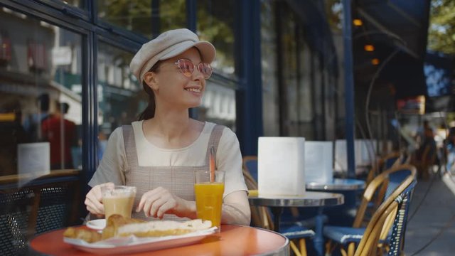 Smiling girl having breakfast in a cafe in Paris