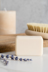 Fototapeta na wymiar Clean soap close up with wooden brush for body massage and candles in white marble bathroom.