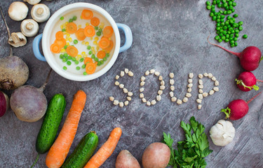 Composition with fresh vegetables on grey background, space for text. Pot with vegetables and word 