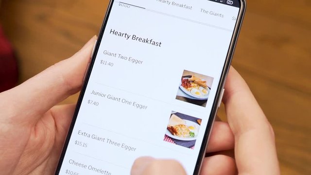 Selection of Healthy Breakfast Food with Delivery in an Online Store in a Mobile App Using a Cell Phone. Close-up of the Smartphone Screen and Fingers. April 2020, Miami