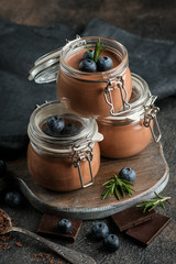 Chocolate mousse in glass jar with berries on a rustic background copy space. Homemade dessert.