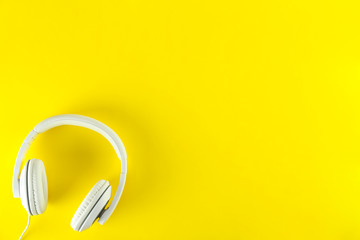 Minimalistic top view composition with white headphones on bright paper textured background with a lot of copy space for your text. Close up, flat lay.