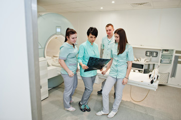 Group of doctors near magnetic resonance imaging machine at hospital.