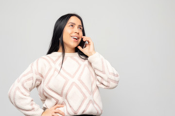 Portrait of a smiling beautiful attractive female student woman talking on the phone, on white-gray background