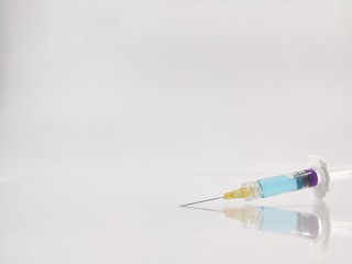 Syringe with blue serum Orange light on top on white background