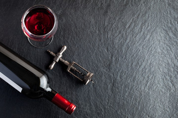 A bottle of wine next to the glass and corkscrew
