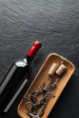 A bottle of wine next to corkscrews.A bottle of wine next to corkscrews.A bottle of wine next to corkscrews