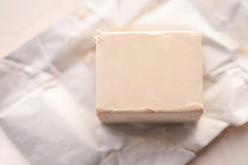 cube of fresh yeast whole and crumbled on a crumled packaging paper background 