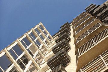 Lviv, Ukraine - 3 4 2020: Facade of a tall multi-storey modern house with balconies and large glass windows. Design of modern architecture. Top view from the bottom. Modern city architecture
