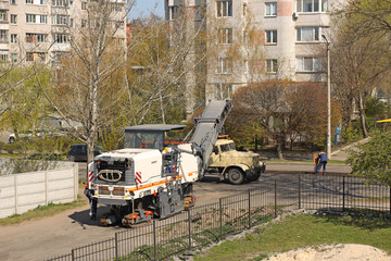 Asphalt removal using heavy machinery. Construction and repair of the road. Modern technology of laying a highway with a solid surface. People work at a construction site. Rolling asphalt