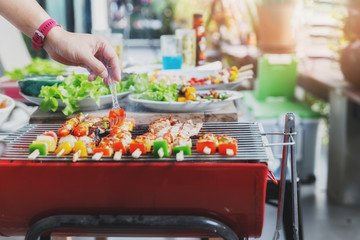 A man grilling pork and barbecue in dinner party. Food, people and family time concept.