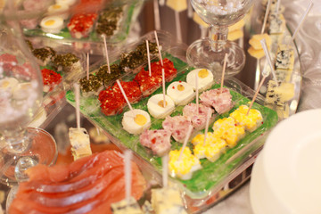 Beautifully decorated catering banquet table with profiteroles, salads and cold snacks. Variety of tasty delicious snacks on the table. Wedding table serving. Meat and vegetables