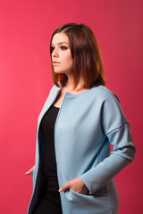 Business redhead girl in a blue jacket posing on a pink background.