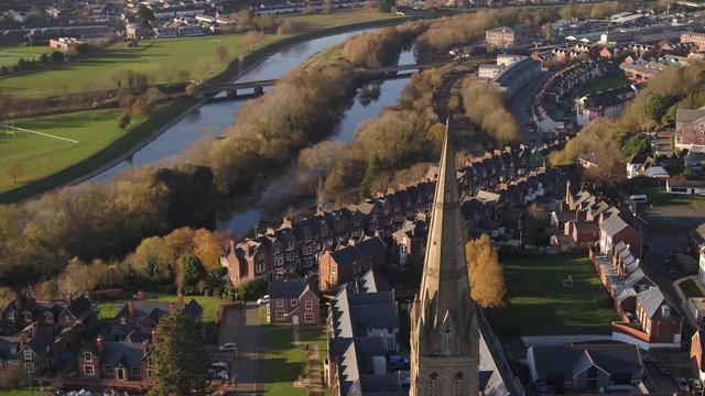 Sweeping aerial view of downtown Exeter, UK. A steeple of a church in the foreground, and the river Exe, the quay, and Exewick in the background