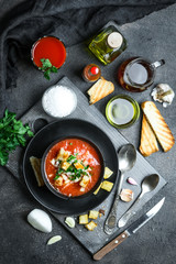 Traditional spanish cold tomato soup gazpacho in a bowl over black slate, stone or concrete background.Top view with copy space.