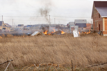 Spring fires of dry grass in area near private residential building. Careless handling of fire