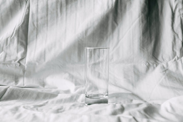 Empty glass on a white cotton sheet background.