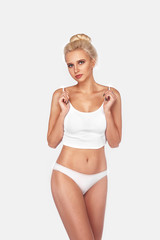 Fototapeta premium Young, slim, healthy and beautiful blonde woman in white lingerie. Sport, fitness, diet, weight loss and healthcare concept. Mockup.