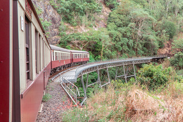 Tourist train journey. Kuranda Scenic Railway Train across rainforest, jungles. Train, train tracks, passenger seats, interior, skyrail, bridge, mountains and landscape.
