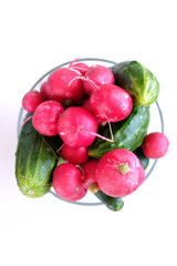 Radishes and cucumbers in a plate on a white background.