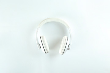 Minimalistic top view composition with white headphones on bright paper textured background with a lot of copy space for your text. Close up, flat lay.