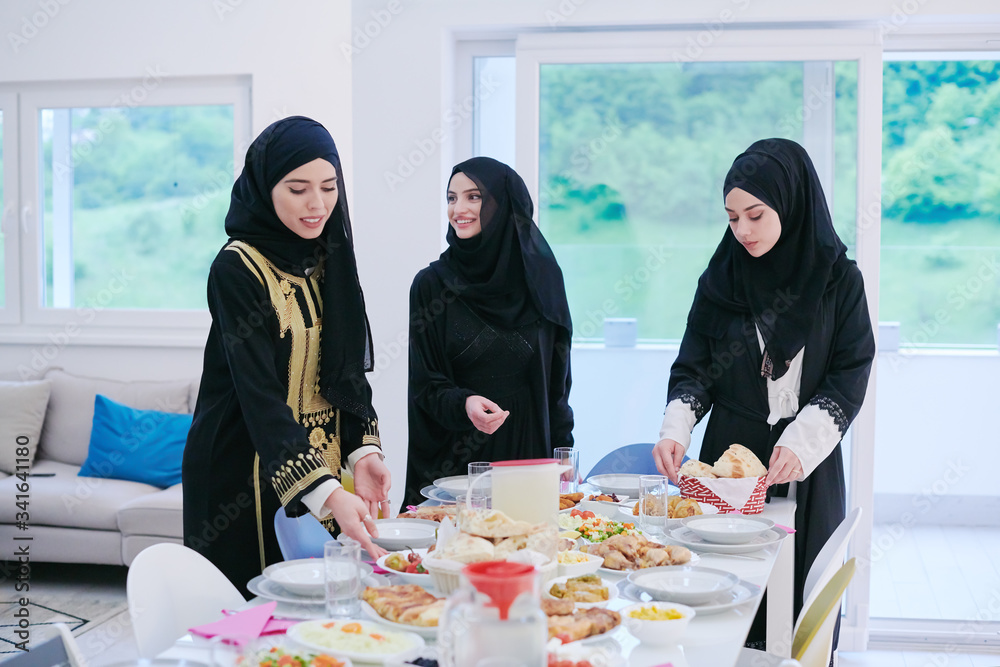 Wall mural young muslim girls serving food on the table for iftar dinner