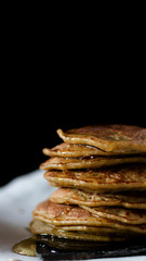 OAT PANCAKES WITH SYRUP ON A BLACK BACKGROUND