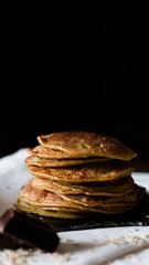 OAT PANCAKES WITH SYRUP ON A BLACK BACKGROUND