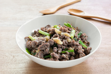 close up of stir fried minced beef with soy sauce in a ceramic bowl on wooden table. asian homemade style food concept.