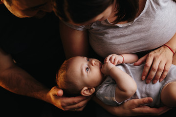 Happy young family with a baby. Parents fun laughing, kissing and hugging their child. 4 months old...