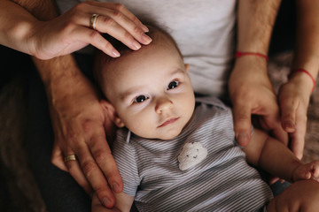 The lying baby in the hand of mother and father close-up. 4 months baby looking