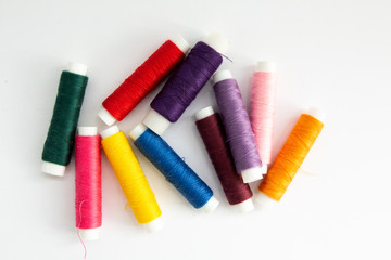 multi-colored spools of thread on a white background