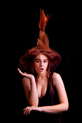 young woman in studio on a black background with flying hair