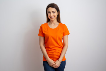 giovane donna timida con maglietta arancione, isolata su sfondo bianco